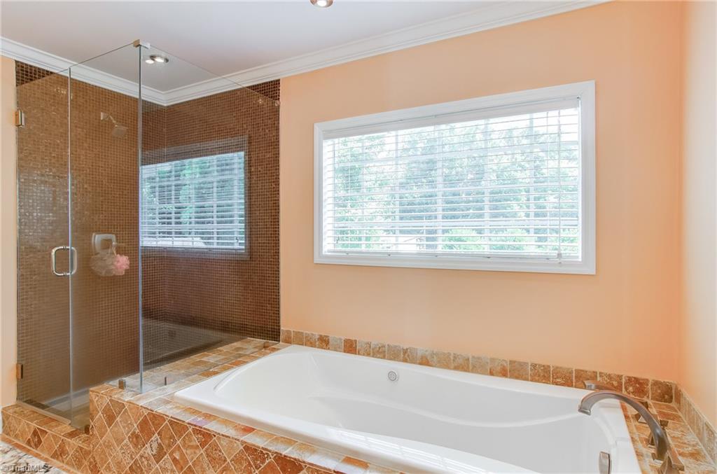 7607 Strawberry Road Summerfield, NC 27358 - Photo 19 of 30 Spacious tiled shower with frame-less doors. Relax in this over-sized tub with air jets! Tub surround has tumbled tile and a hand held sprayer.