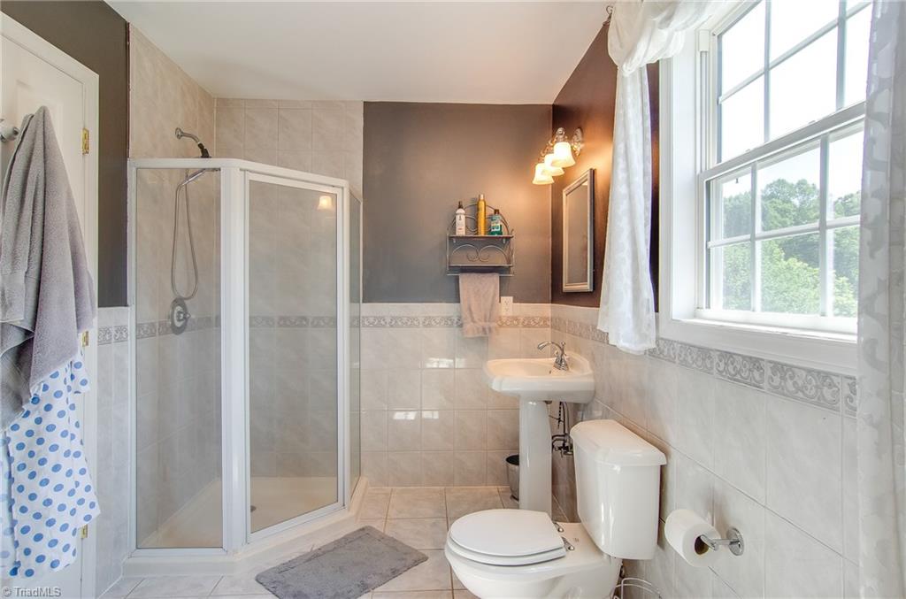 7607 Strawberry Road Summerfield, NC 27358 - Photo 29 of 30 Well appointed upstairs bath has walk in shower and impressive tile.