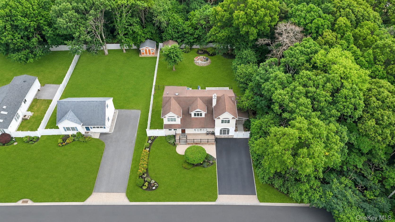 19 Joan Road Bay Shore, NY 11706 - Photo 3 of 50 Expansive property featuring a multi-level residence with a brown shingle roof and white siding, an attached paved driveway, and a manicured lawn
