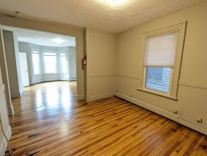 a view of an empty room with wooden floor and a window