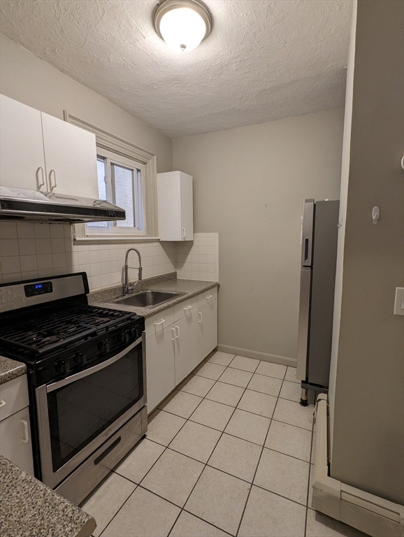 219 Green Street, Unit 2 Cambridge, MA 02139 - Photo 3 of 7 a kitchen with stainless steel appliances granite countertop a stove a refrigerator and a microwave