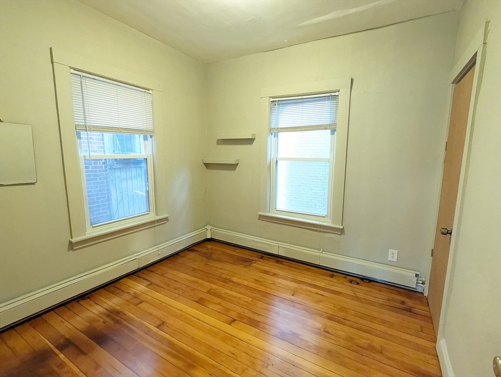 219 Green Street, Unit 2 Cambridge, MA 02139 - Photo 5 of 7 a view of an empty room with wooden floor and a window