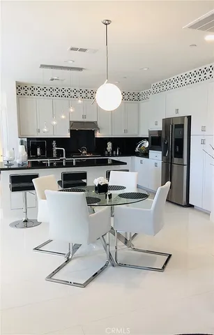 a kitchen with stainless steel appliances kitchen island granite countertop a sink a stove a refrigerator cabinets and chairs