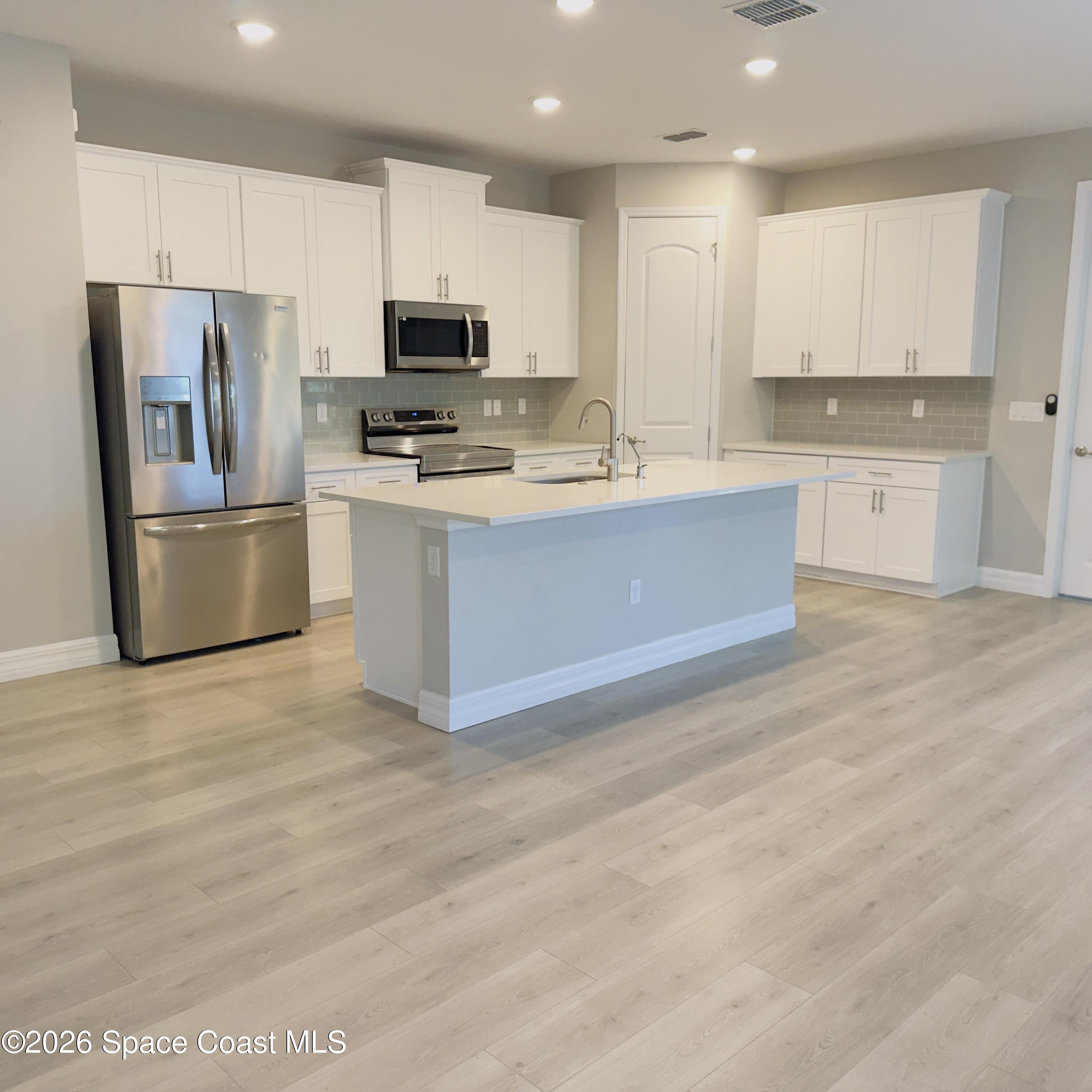 1376 Torgerson Road Southeast Palm Bay, FL 32909 - Photo 4 of 15 a large kitchen with cabinets stainless steel appliances and a counter space