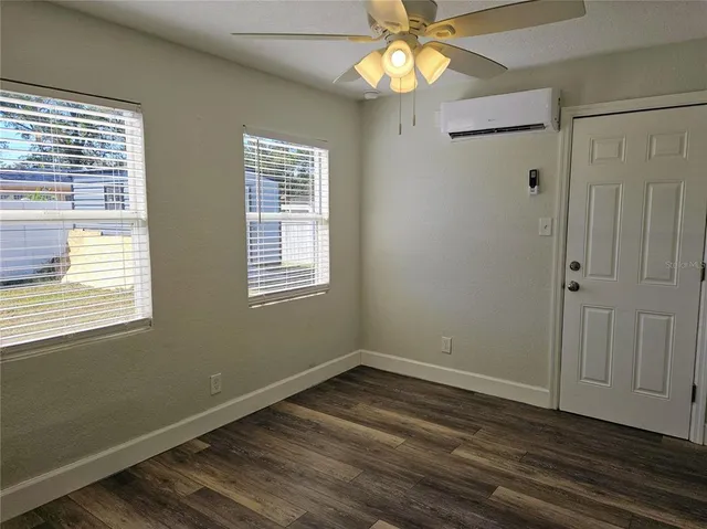 a view of an empty room with wooden floor and a window