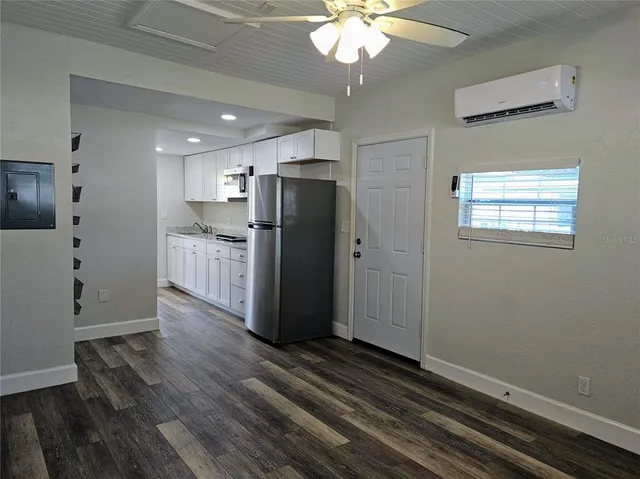 a view of a refrigerator in kitchen and an empty room with wooden floor