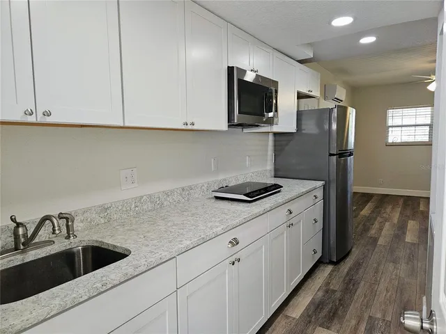 a kitchen with stainless steel appliances granite countertop a sink a stove and a refrigerator with wooden floor