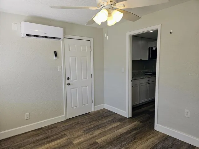 a view of empty room with wooden floor and fan