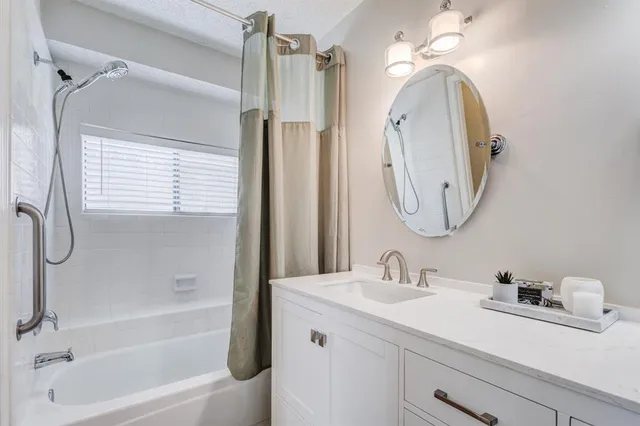 a bathroom with a granite countertop sink a mirror a vanity and a bathtub