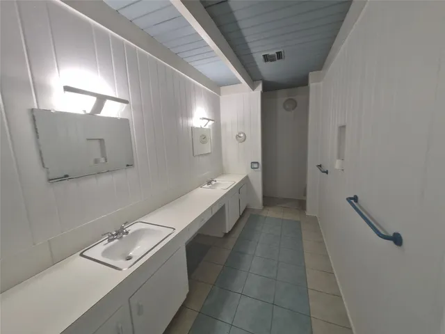 a bathroom with a double vanity sink and mirror with bathtub