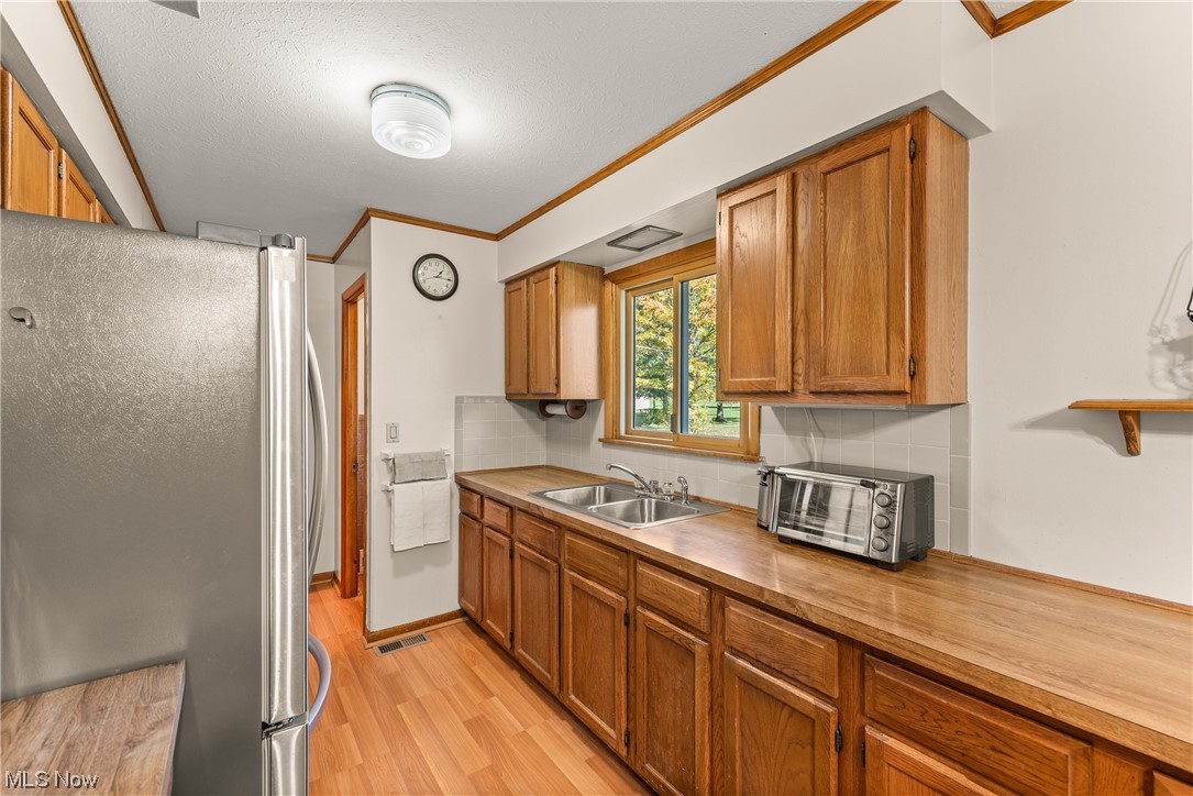 2151 Lester Road Valley City, OH 44280 - Photo 10 of 24 Kitchen featuring stainless steel refrigerator, tasteful backsplash, sink, light hardwood / wood-style floors, and ornamental molding