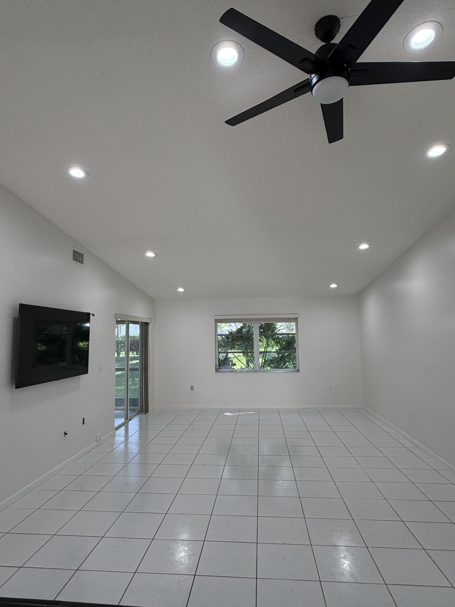 6356 Pointe Pleasant Circle, Unit G Delray Beach, FL 33484 - Photo 4 of 31 a view of an empty room with windows and a ceiling fan