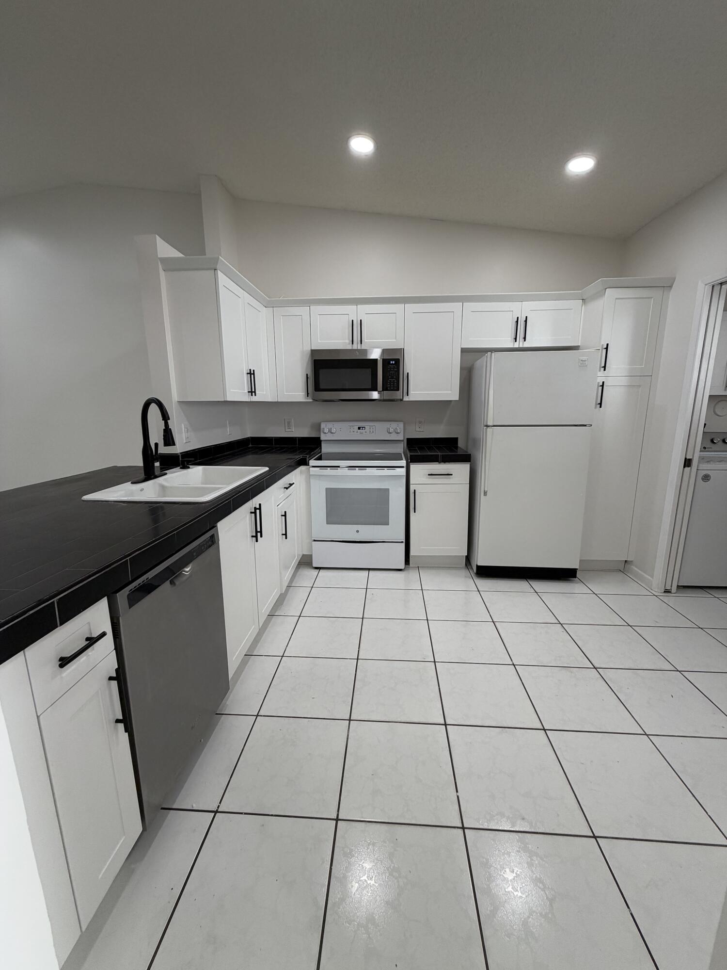 6356 Pointe Pleasant Circle, Unit G Delray Beach, FL 33484 - Photo 6 of 31 a kitchen with a sink a stove and refrigerator