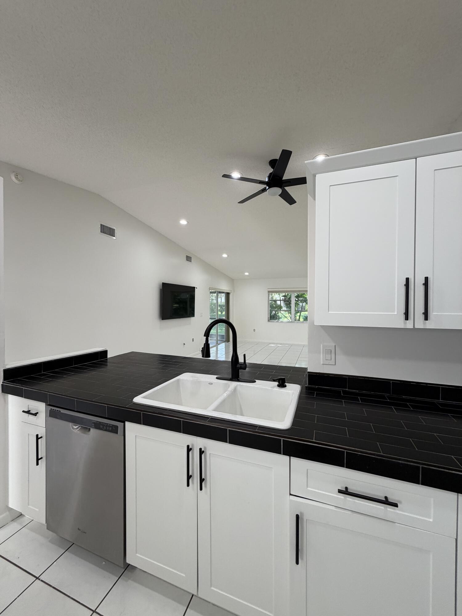 6356 Pointe Pleasant Circle, Unit G Delray Beach, FL 33484 - Photo 7 of 31 a kitchen with granite countertop a sink and white cabinets