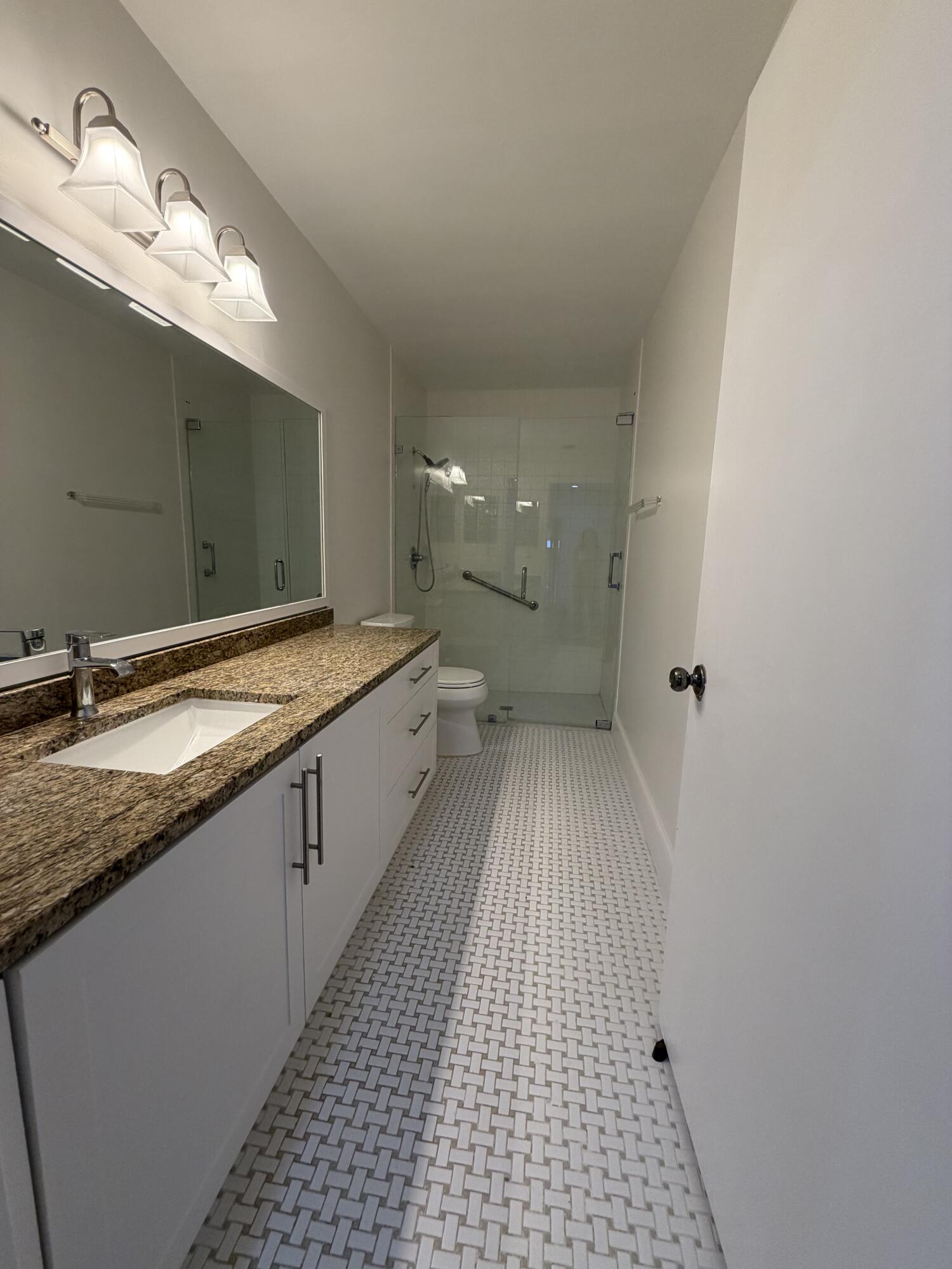 6356 Pointe Pleasant Circle, Unit G Delray Beach, FL 33484 - Photo 10 of 31 a spacious bathroom with a granite countertop sink a toilet and a mirror