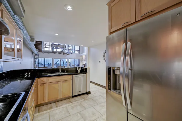 a kitchen with stainless steel appliances granite countertop a sink refrigerator and cabinets
