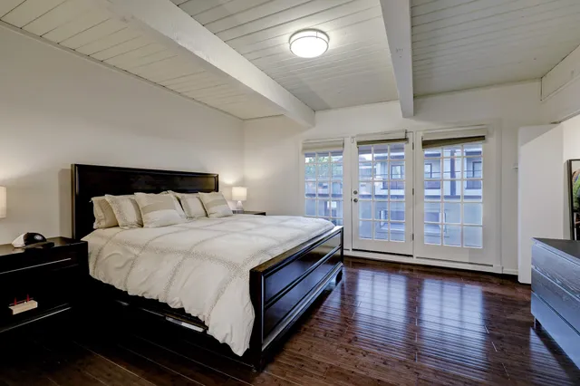 a spacious bedroom with a bed and wooden floor