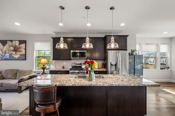 a kitchen with stainless steel appliances granite countertop a stove top oven a sink dishwasher a dining table and chairs with wooden floor