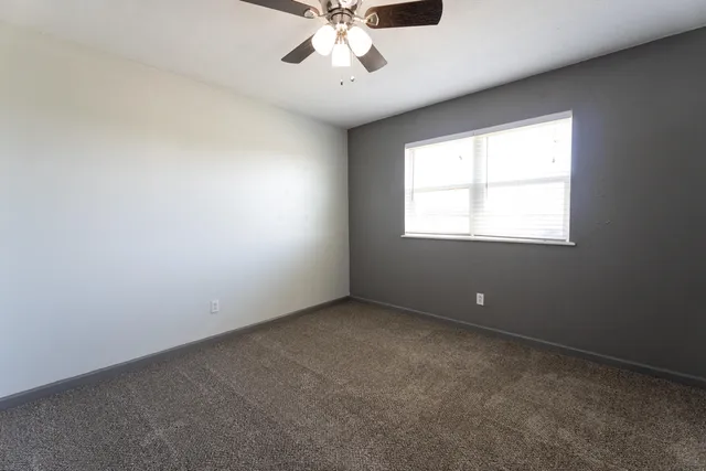 an empty room with a window and a fan