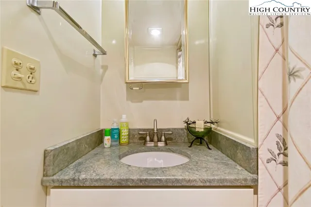 a bathroom with a granite countertop sink a mirror and shower