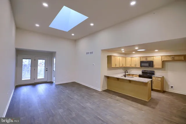 a living room with stainless steel appliances granite countertop furniture wooden floor and a view of kitchen