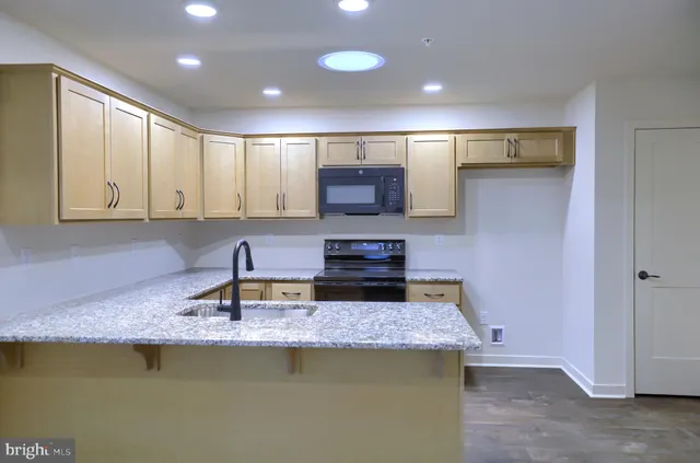 a kitchen with kitchen island granite countertop a sink a stove and cabinets