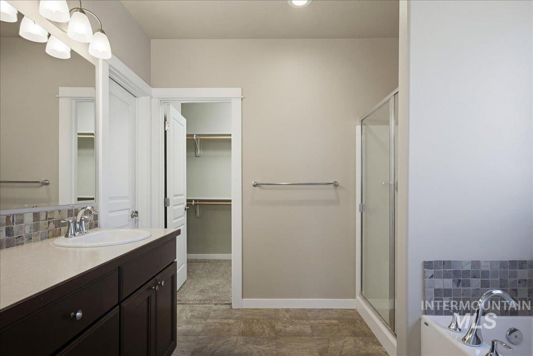 12460 West Azure Street Boise, ID 83713 - Photo 16 of 34 Contemporary bathroom featuring a dark wood vanity with a single basin, light-toned countertop, and mosaic tile backsplash