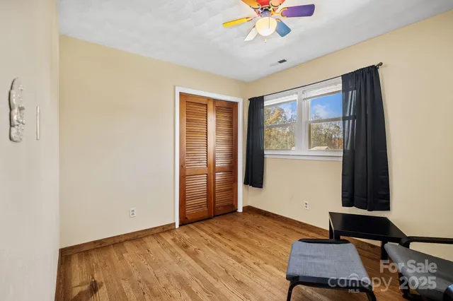 a view of an empty room with a window and wooden floor
