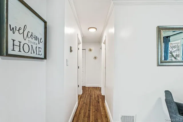 a view of a hallway with wooden floor and a bathroom