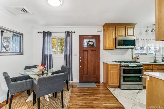 a kitchen with stainless steel appliances granite countertop a stove top oven a sink dishwasher and a dining table with chairs