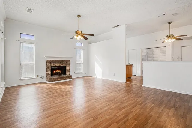 a view of empty room with wooden floor fireplace and a window