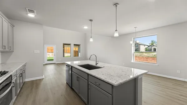 a kitchen with granite countertop kitchen island stainless steel appliances a sink stove and wooden floor