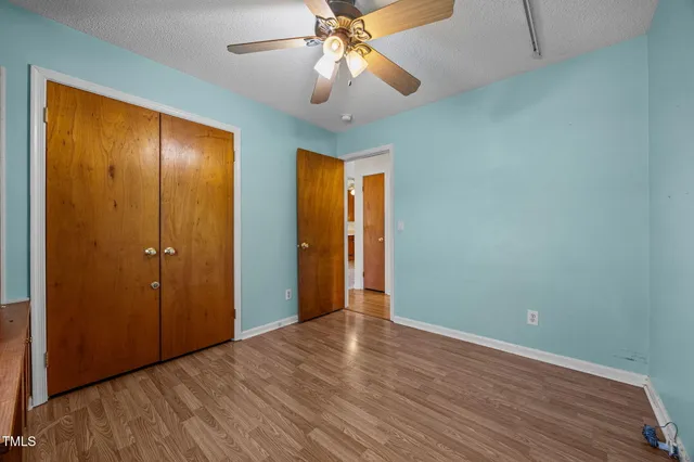 wooden floor in an empty room with a chandelier fan