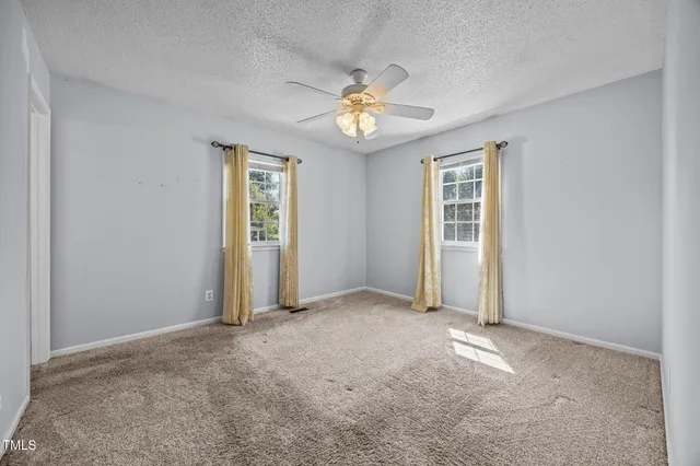 an empty room with windows and ceiling fan