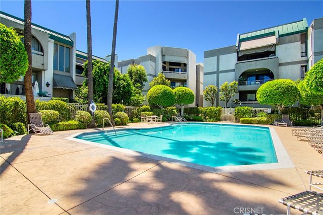 a view of a street with potted plants and more windows