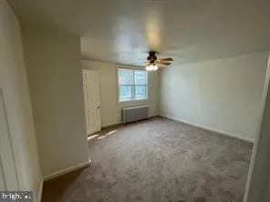 an empty room with windows and chandelier fan
