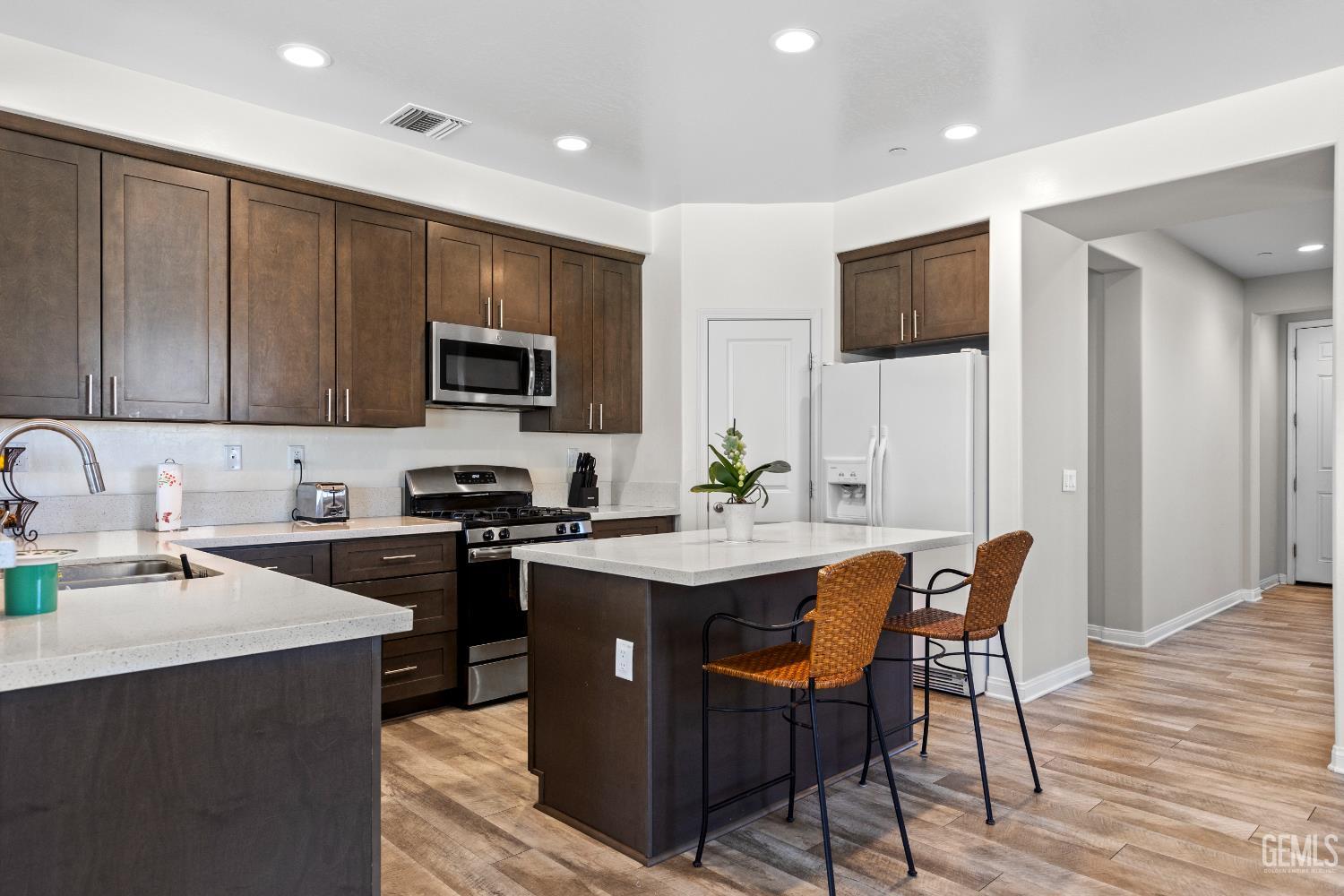 Undisclosed Address Tehachapi, CA 93561 - Photo 15 of 43 a kitchen with stainless steel appliances granite countertop a stove top oven a sink dishwasher a dining table and chairs with wooden floor