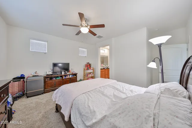 a bedroom with a bed a chandelier and a flat screen tv