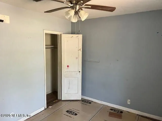 an empty room with wooden floor closet and fan