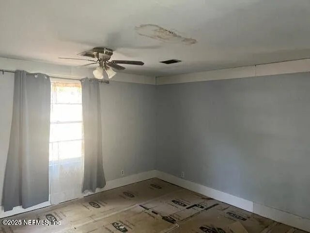 an empty room with a window and a fan