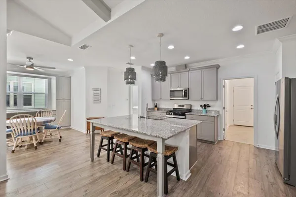 an open kitchen with kitchen island wooden floor center island and stainless steel appliances