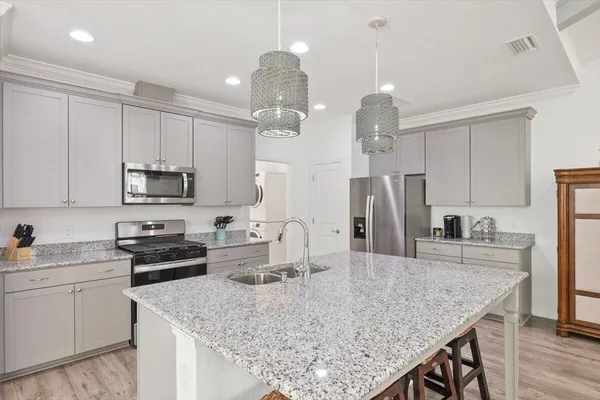 a kitchen with kitchen island granite countertop a sink a center island and stainless steel appliances