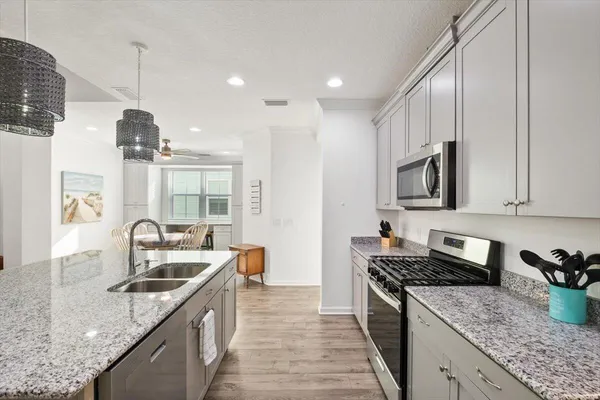 a kitchen with granite countertop stainless steel appliances a sink a stove top oven a counter space and cabinets