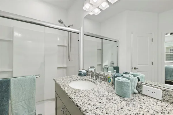a bathroom with a granite countertop sink a mirror and shower