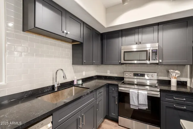 a kitchen with stainless steel appliances granite countertop a sink a stove microwave and cabinets