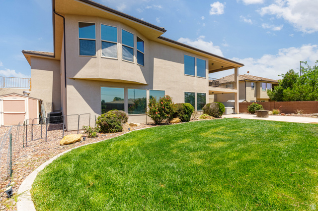 2005 West 450 S Circle St. George, UT 84770 - Photo 41 of 57 Expansive backyard featuring a manicured lawn, stone-edged landscaping, and a stucco exterior