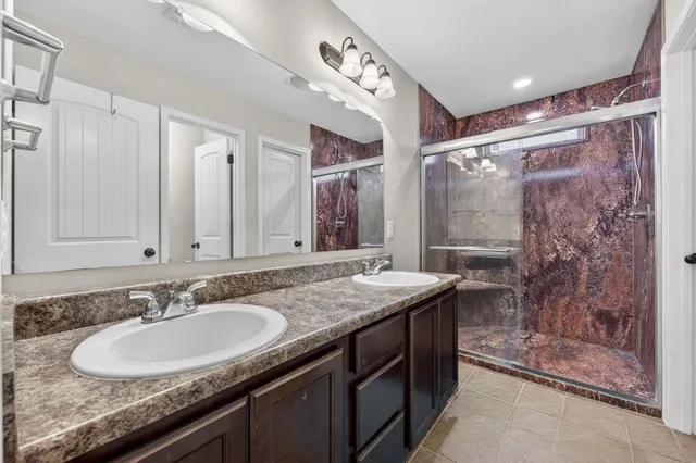 a bathroom with a granite countertop sink a mirror a and a shower