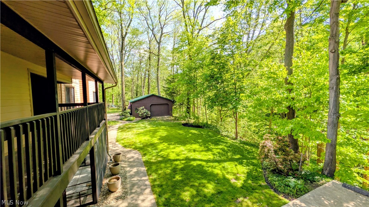 6409 Old Woods Road Ashtabula, OH 44004 - Photo 37 of 43 Spacious backyard featuring a manicured lawn, established trees, and a detached outbuilding with a garage door