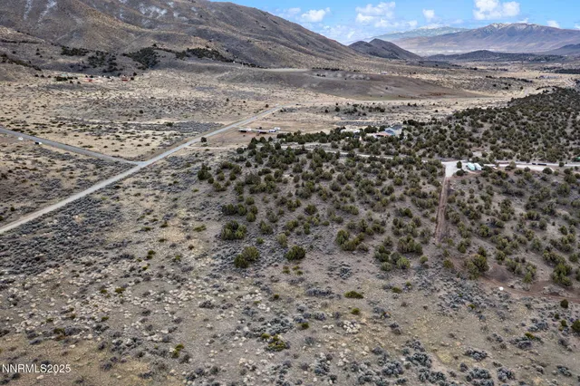 a view of a dry field with mountains in the background