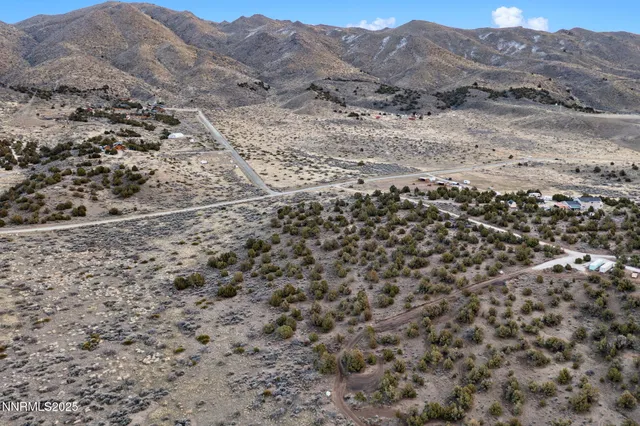 a view of a dry field with mountains in the background